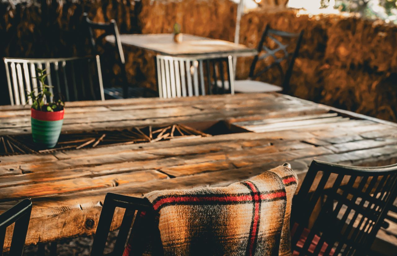 Charming rustic outdoor seating area with a cozy blanket and potted plant on a wooden table.